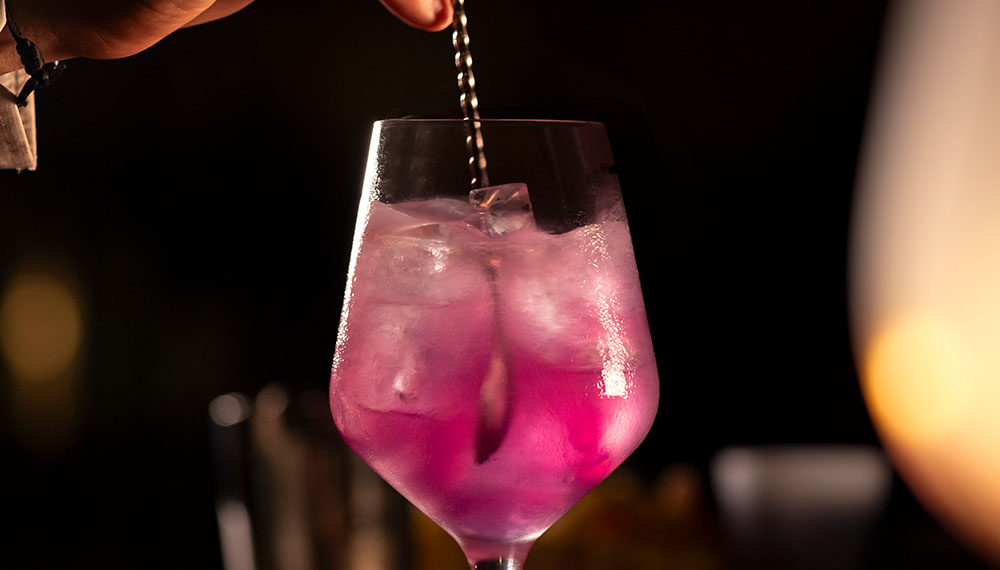 Pink cocktail being stirred by bartender