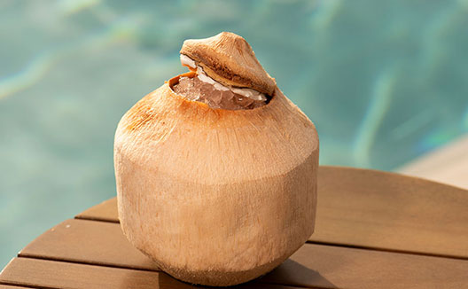 Open coconut sitting in front of pool